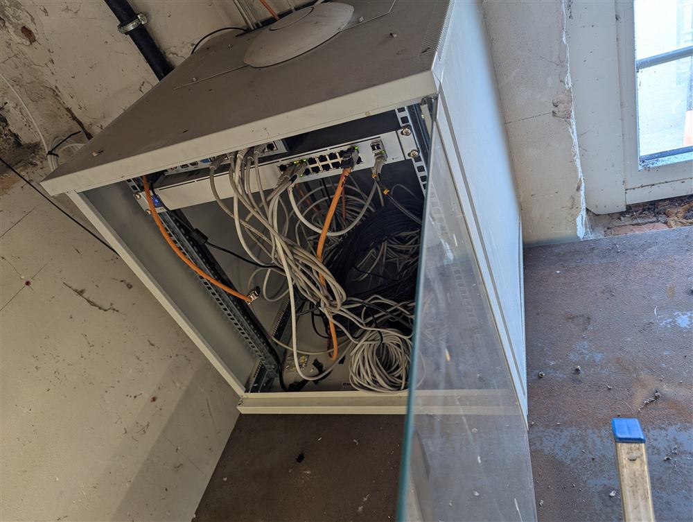 Offener Netzwerkschrank mit dicht gebündelten, unübersichtlichen Kabeln